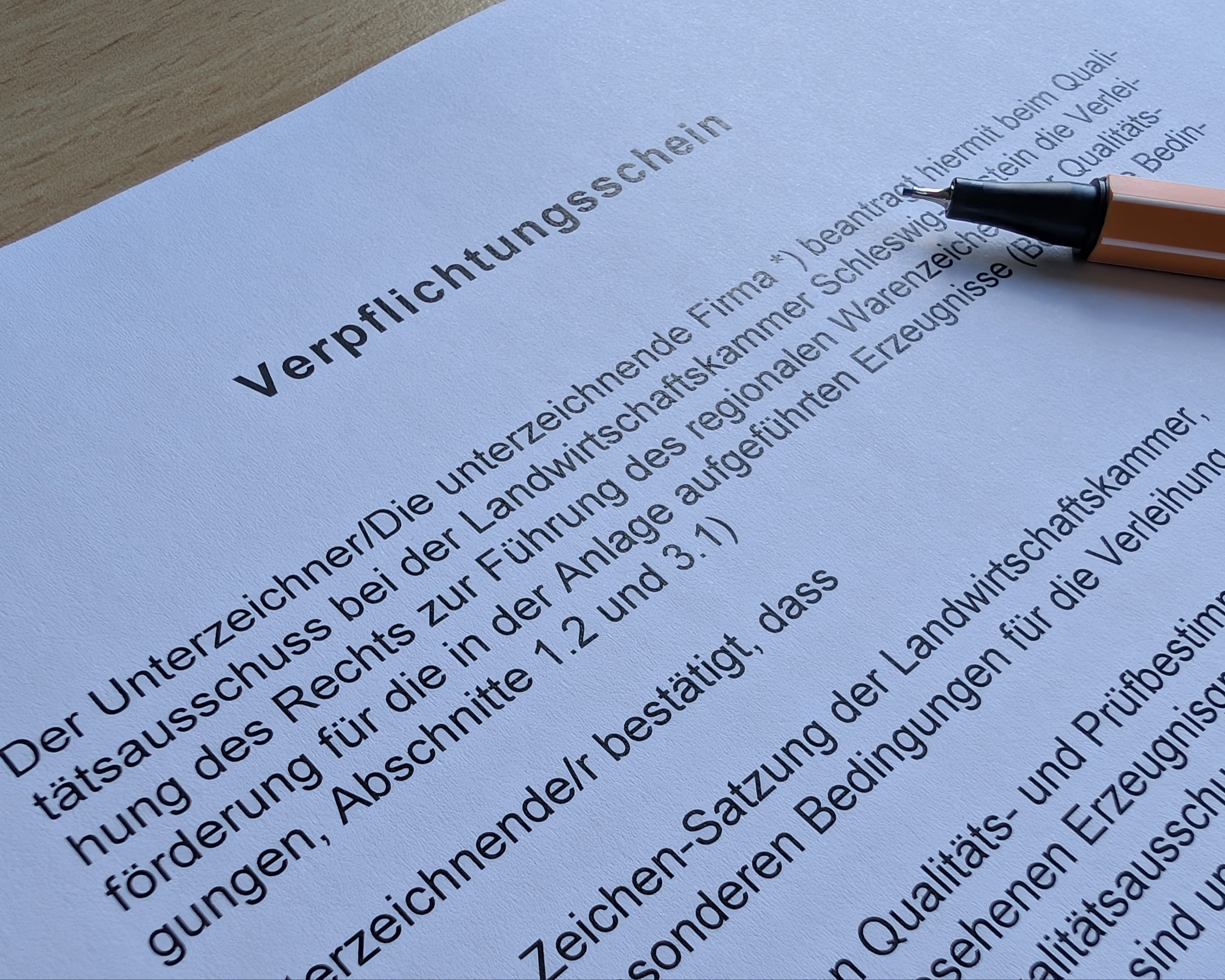 Formular, das von einer Hand mit einem grünen Stift ausgefüllt wird