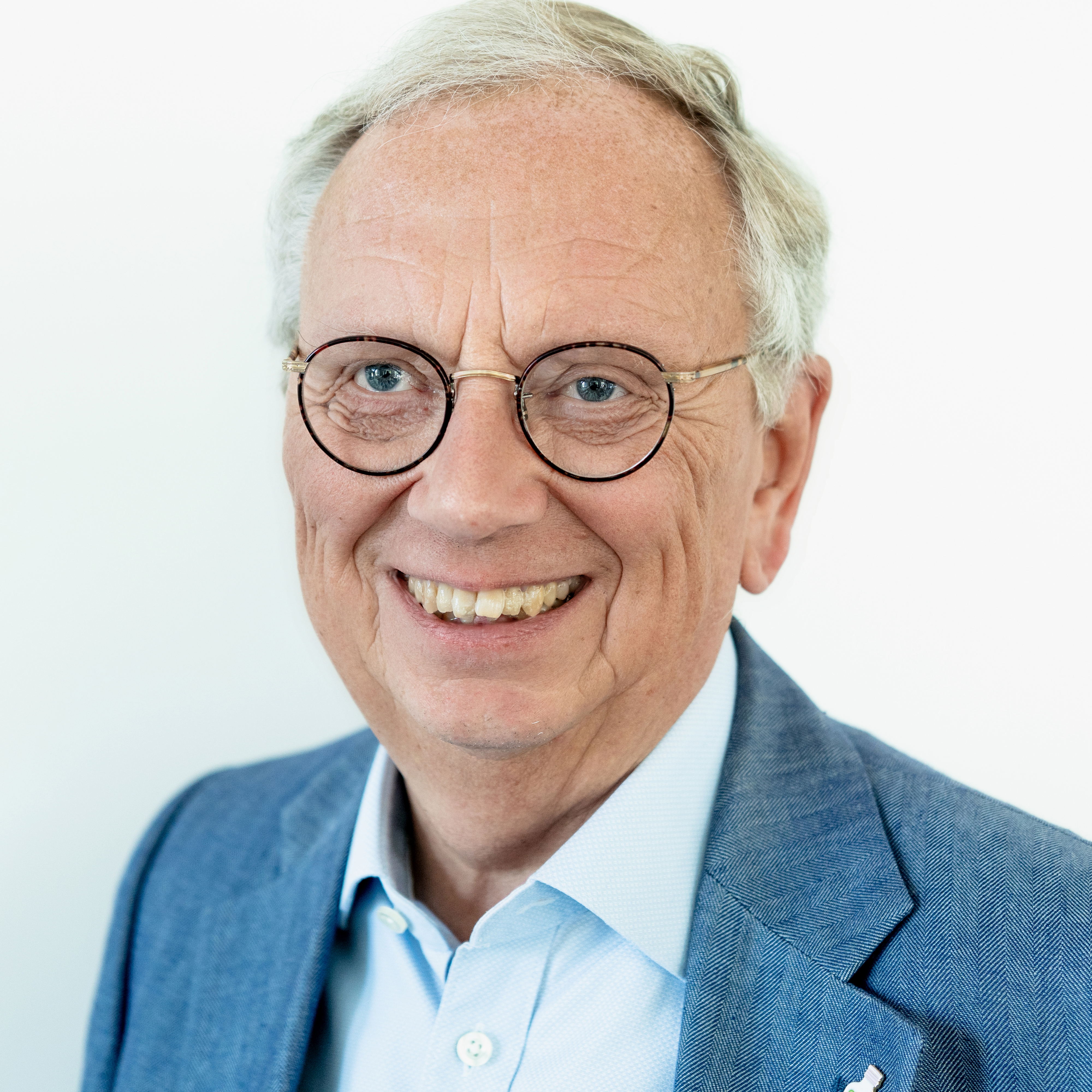 Mann mit grauen Haaren und Brille lächelt in die Kamera